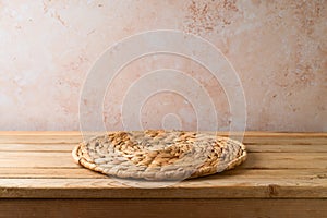 Wicker place mat on wooden table over stone wall background. Kitchen counter mock up for design and product display