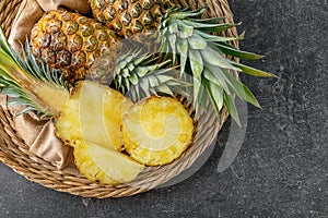 Wicker plate with delicious pineapples on grey background photo