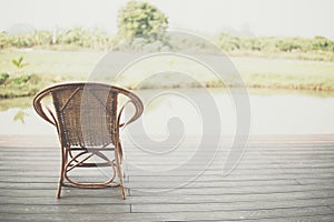 Wicker rattan chair on balcony terrace patio near pond