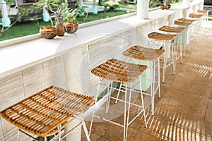 Wicker rattan chairs on bar counter. Trendy furniture design. Summer cafe