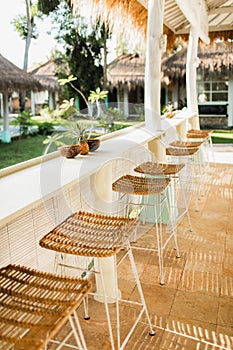 Wicker rattan chairs on bar counter. Trendy furniture design. Summer cafe