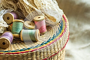 Wicker rattan crafts and sewing supply box, wooden spools, rolls of lace, linen cloth background, hobby fashion concept