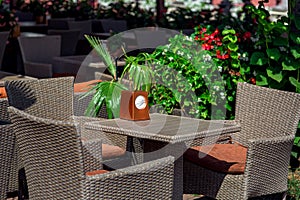 Wicker rattan plastic fittings on terrace of street restaurant lit by sun.