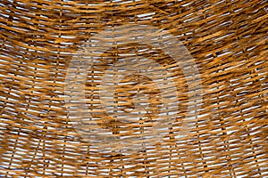 Wicker roof beach umbrella. The texture of wicker twigs through which you can see the blue sky. Brown color. Natural background