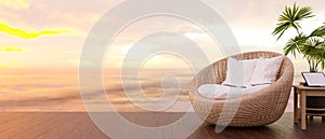 Wicker round chair, portable tablet on table, sunset over sea in background