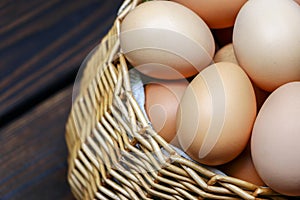 wicker straw basket with eggs on wooden background.