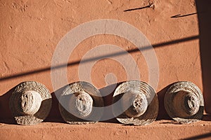 Wicker straw hats on background of terracotta color wall in Morocco