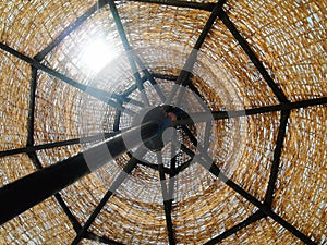 The wicker sun umbrella on the blue sky background. Closeup.