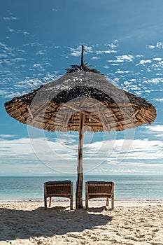 Wicker umbrella and sunbeds on paradise beach