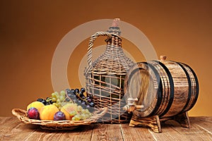 Wicker wine bottle, grapes and wooden barrel