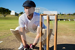 Wicket keeper crouching by stumps during match