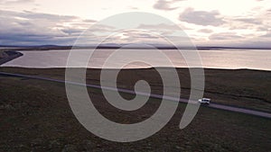 Wide aerial follow white 4x4 vehicle from a side view ocean in background