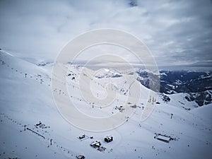Wide aerial panorama of snowy mountain ridge on winter sunrise. Stunning mountains range covered with snow powder on ski