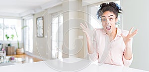 Wide angle of beautiful african american woman with afro hair celebrating crazy and amazed for success with arms raised and open
