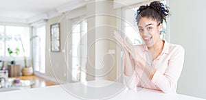 Wide angle of beautiful african american woman with afro hair clapping and applauding happy and joyful, smiling proud hands