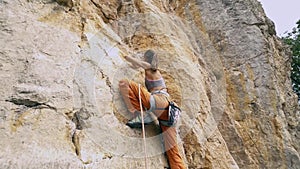 Wide angle bottom view Young fit woman rock climbing on sport route outdoors