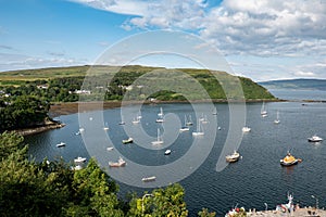 The wide-angle cityscape of harbour in Portree, Isle of Skye, Scotland at sunset with ships and boats