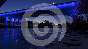 Wide angle cityscape of Minneapolis from under the iconic blue lit 35W Bridge