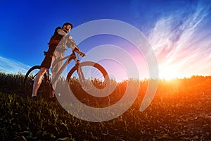 Wide angle of the cyclist standing on the trail on the field against beautiful landscape.