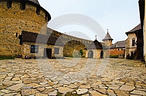 Wide-angle landscape view of courtyard with ancient stone buildings in the old medieval castle. High stone wall with towers