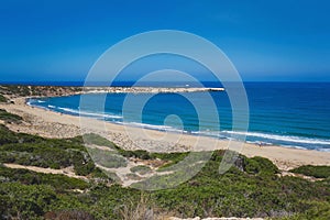 Wide angle landscape view of a empty sandy beach with the sea and its waves on a nice summer day with blue sky