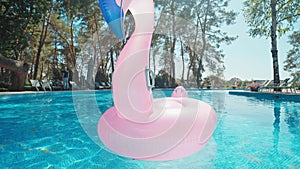 Wide angle lens shooting of lonely rubber ring pink flamingo in pool