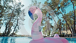 Wide angle lens shooting of lonely rubber ring pink flamingo in pool