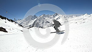 A wide angle male skier aged in black equipment and white helmet with ski poles rides on a snowy slope on a sunny day