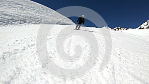 A wide angle male skier aged in black equipment and white helmet with ski poles rides on a snowy slope on a sunny day