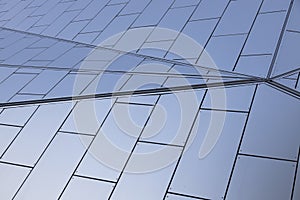 Wide angle of metal white tiles with blueness shade on wall of building with geometric design