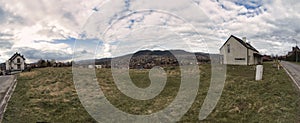 Wide angle Panorama shot of a vintage a shaped wooden house in the middle of nowhere. Countryside view of a home against dramatic