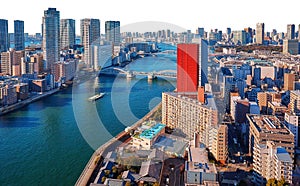 Wide angle panoramic view of Sumida river under blue sky in Tokyo with wavy water, boats, bridges and skyscrapers