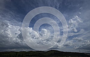 Wide angle photo of cloudy blue sky. Mountains appear under the photo. Width angle