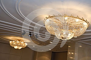 A pair of pendant lighting hanging from a cornice ceiling shinning warm amber golden light rays