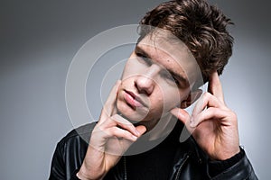 Wide angle portrait Young male model in black clothes posing in studio white background. Guy wearing black classic leather jacket