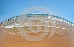 Wide angle sandy beach on the Mediterranean Sea, blue sky and sea, the fish-eye.