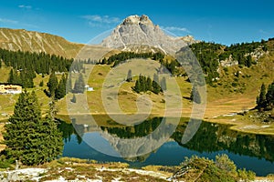 Wide-angle scenic landscape of a mountain peak with a lake below. photo