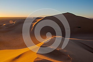 Wide angle shoot of sand desert dunes of Erg Chigaga moved by the wind. The gates of the Sahara, at sunrise. Morocco. Concept of