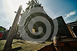 Wide-angle shot against the sun from a historic black locomotive made of iron