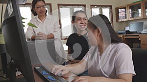 Wide angle shot of Asian women co-workers in workplace including person with blindness disability using computer with refreshable