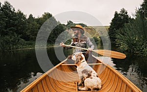 Wide angle shot: man and his dog in wooden canoe.