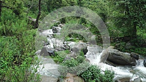 A wide angle shot of a river flowing through the forest with mountain surrounding in India. Dehradun city of uttarakhand