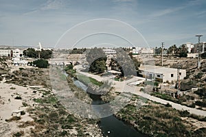 Wide angle shot of a river surrounded by buildings and grass on an arid landscape