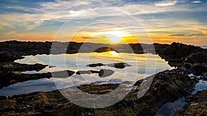 Wide angle shot of the sun shining overt the lake surrounded by cliffs