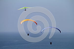 Wide angle shot of three parachutes flying over the ocean