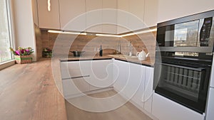 Wide angle tilt shot of modern white and wooden beige kitchen interior
