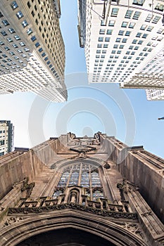 Wide angle upward view of Trinity Church at Broadway and Wall Street with surrounding skyscrapers, Lower Manhattan, New