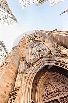 Wide angle upward view of Trinity Church at Broadway and Wall Street with surrounding skyscrapers, Lower Manhattan, New