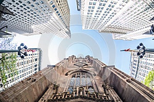 Wide angle upward view of Trinity Church at Broadway and Wall Street with surrounding skyscrapers, Lower Manhattan, New