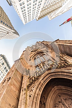 Wide angle upward view of Trinity Church at Broadway and Wall Street with surrounding skyscrapers, Lower Manhattan, New